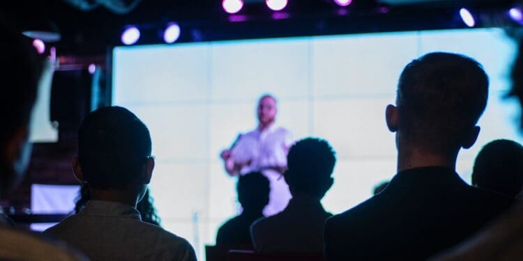 man in black suit standing in front of people