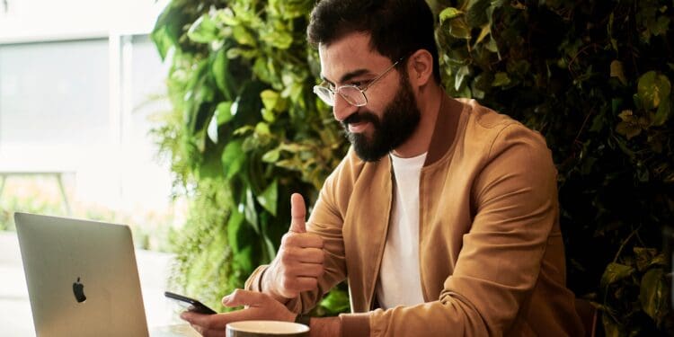 man in brown jacket sitting at a table looking at laptop