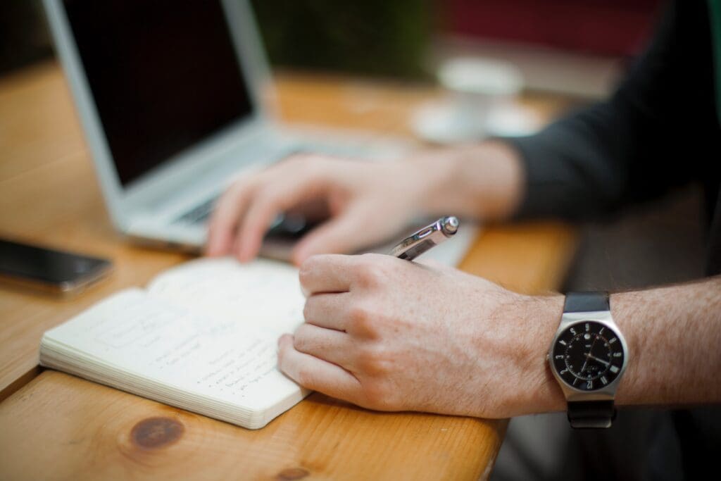 man with wristwatch writing a journal