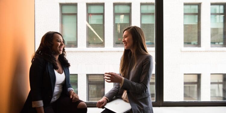 two woman sitting by the window laughing