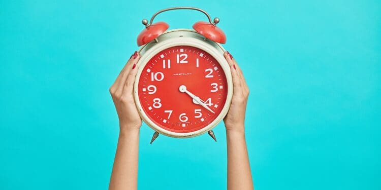 person holding red and beige twin bell analog alarm clock