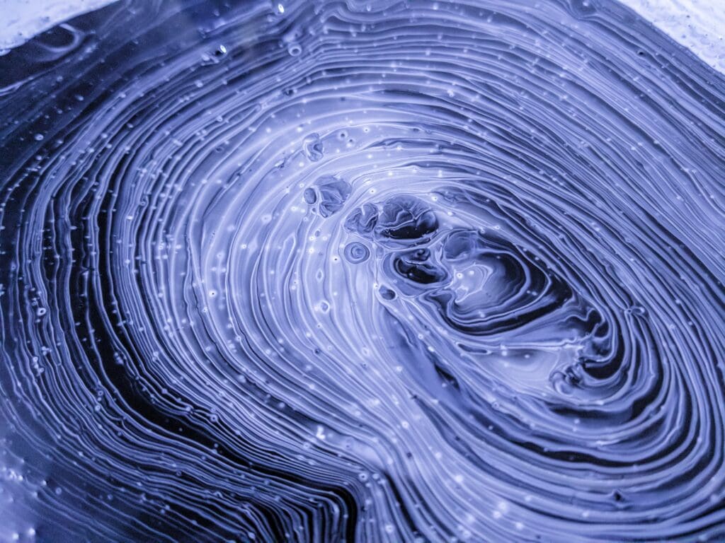 This experimental painting features swirls of black, grey, purple, and white paints. As the paints began to dry, I took this closeup.

The technique I use to create this kind of paint texture is called “fluid art,” and it relies on mixing a variety of mediums into acrylic paints to influence how they interact. I’ll use materials like glue, isopropyl alcohol, liquid silicone, and a butane torch.