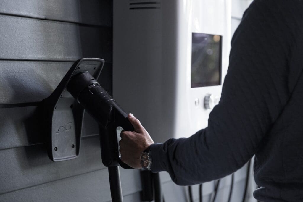 A home EV charging connector hooked to the wall of a garage.
