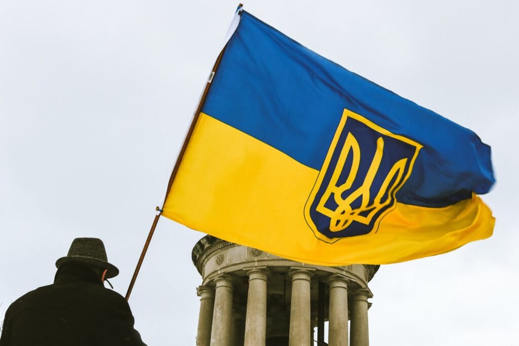 A man waving the Ukrainian flag with the  Coat of arms of Ukraine insignia.