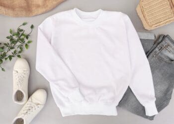 Blank and plain white sweater mockup photo with jeans and sneakers on the background. Use it to display your apparel design.