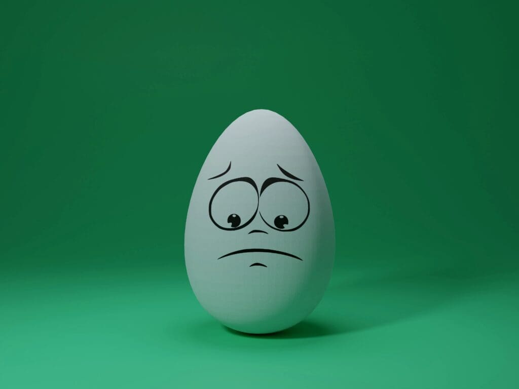 cute looking and sad egg sitting on the ground.