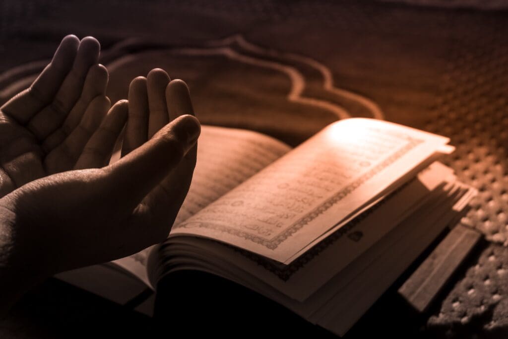 A photo of a boy praying in front of the Holy Quran in a mosque