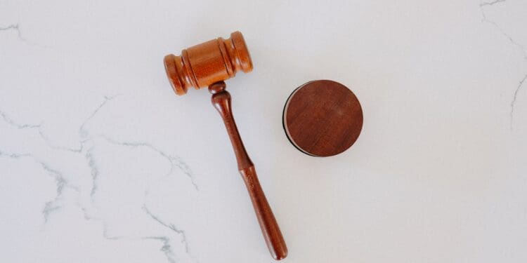 A wooden gavel on a white marble backdrop.