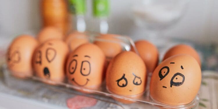 Creative background with chicken eggs in the kitchen close-up. Trendy eggs with faces painted on their shells. Emotional faces on eggs - festive background, design for website about psychology and business