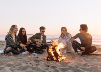 group of people sitting on ground with bonfire during daytime