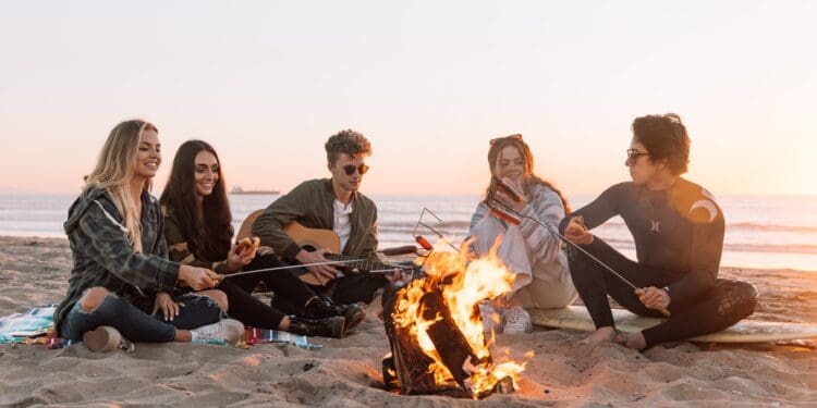 group of people sitting on ground with bonfire during daytime